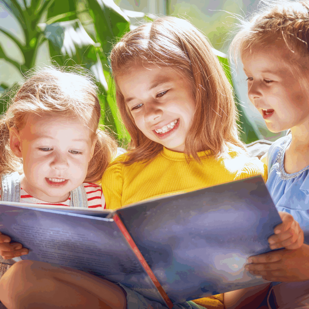 Smiling girls sharing a book indoors